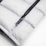 Close-up of a light gray quilted jacket with a black zipper and a purple brand pull tab reading ICEFLAME/XL.