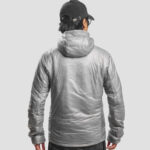 Person wearing a metallic silver puffer jacket with hood, viewed from behind, wearing a black cap.